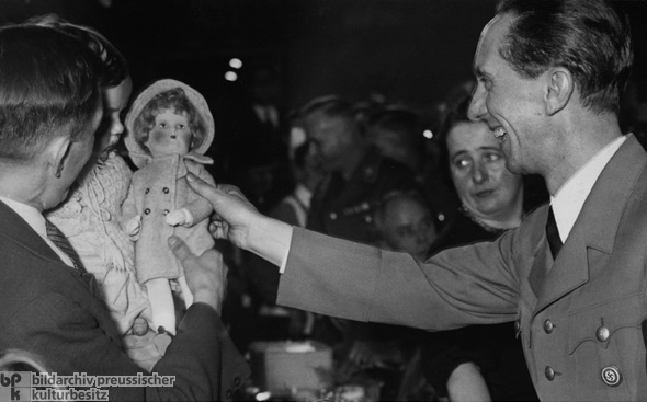 Joseph Goebbels beschenkt zu Weihnachten im Rahmen einer Veranstaltung des Winterhilfswerks ein Kind (1. Dezember 1936)